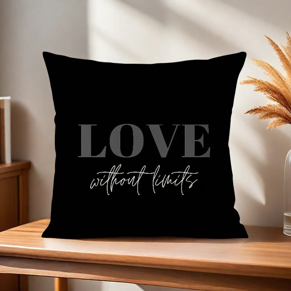 Black pillow with 'LOVE without limits' text on a wooden surface with a plant in the background