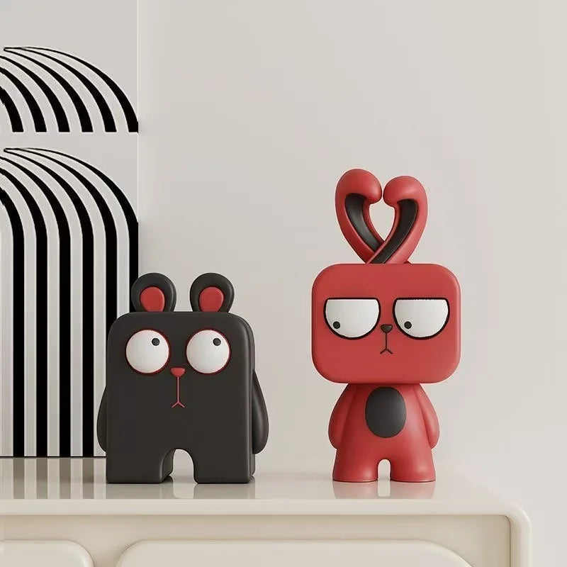 Two cartoonish animal figurines, one black and one red, on a light surface with a striped background.