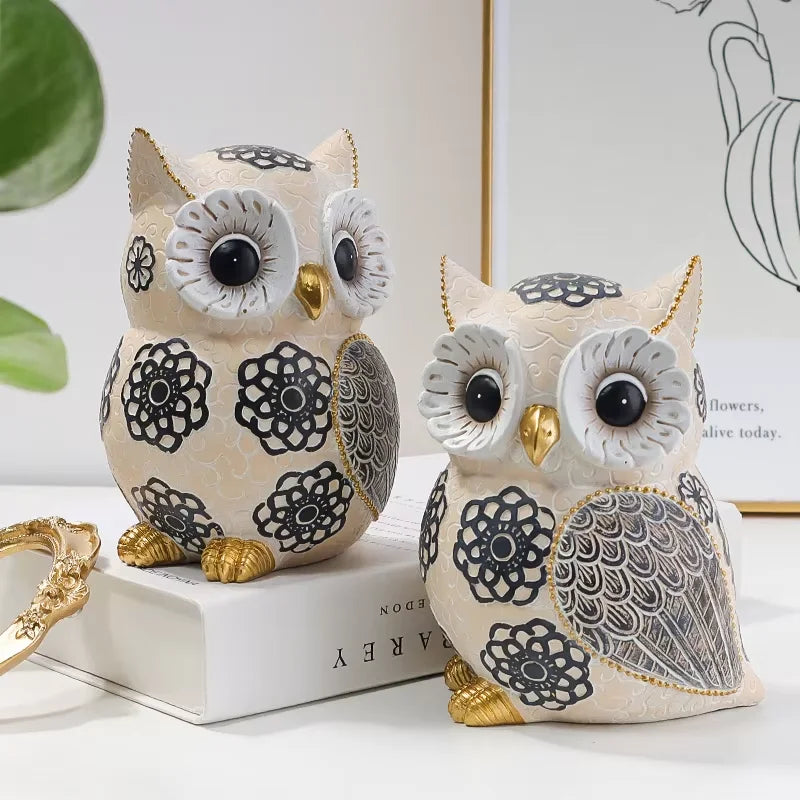 Decorative cream resin owl ornament with black floral patterns, textured grey wings and gold accents displayed as elegant home décor.