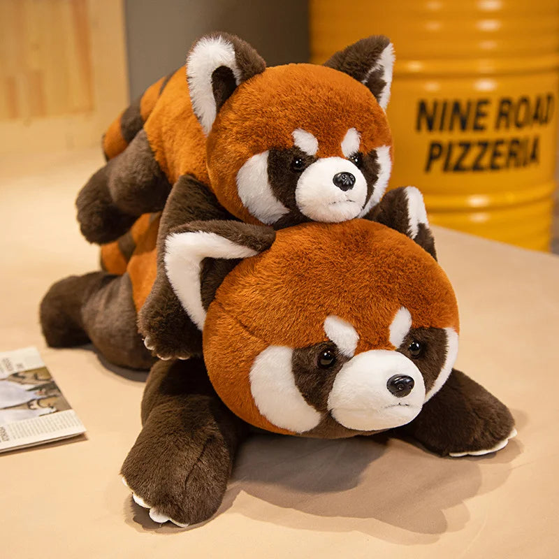 Two plush red pandas on a table with a yellow container labeled 'Nine Road Pizzeria' in the background.