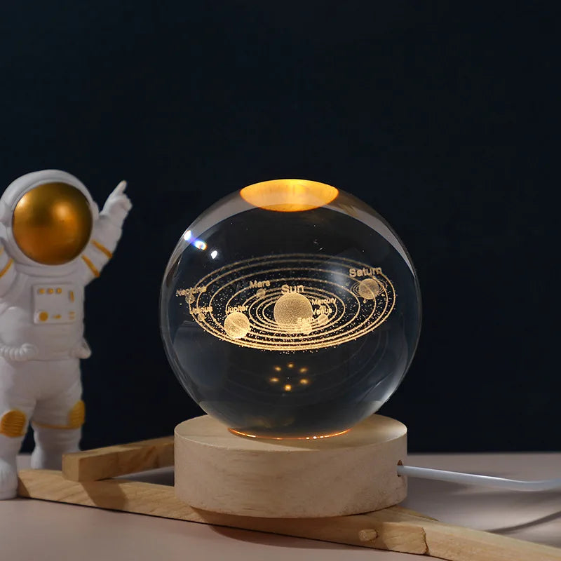Clear crystal ball with solar system design on a wooden base, next to an astronaut figurine.