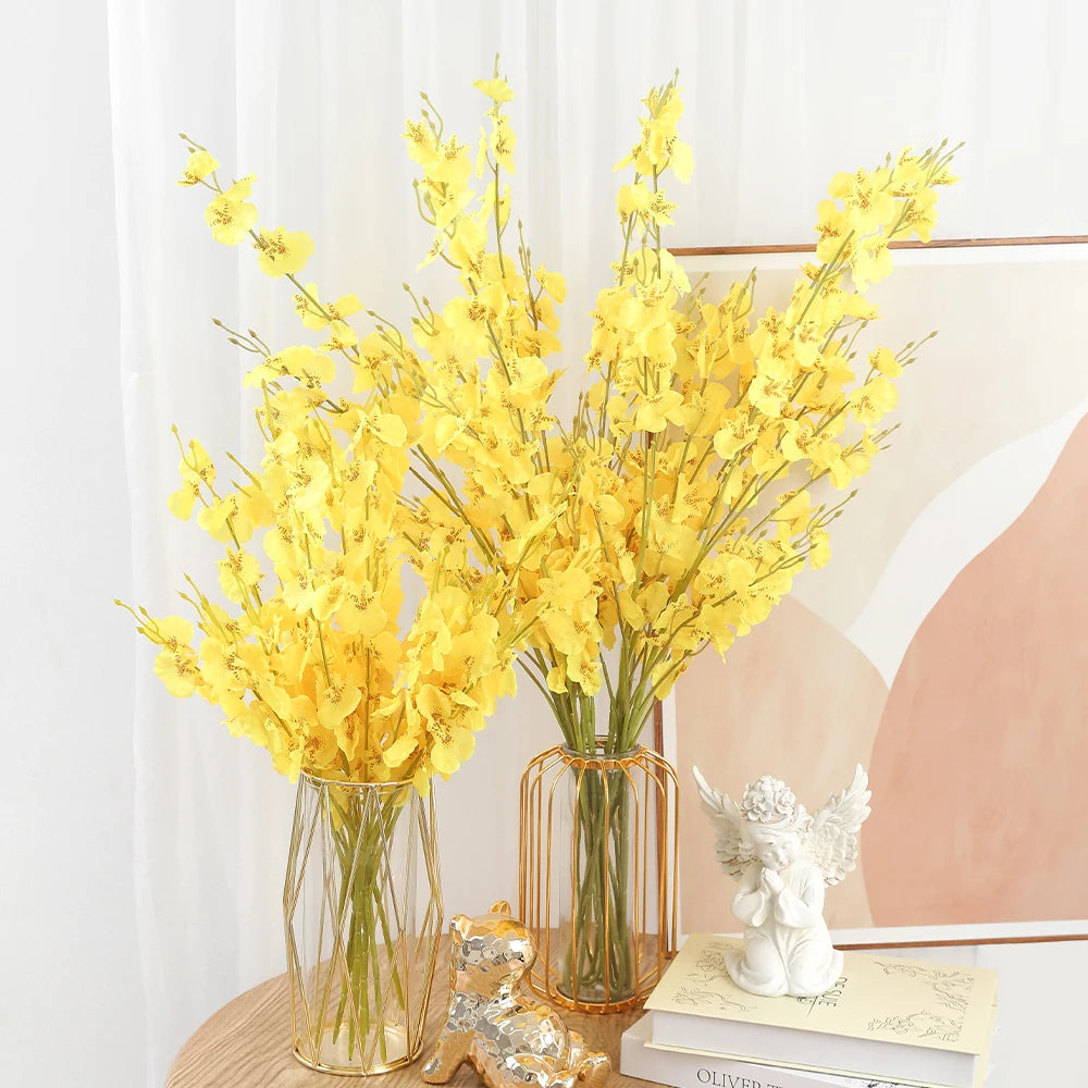 Two vases with yellow flowers on a table against a white curtain background