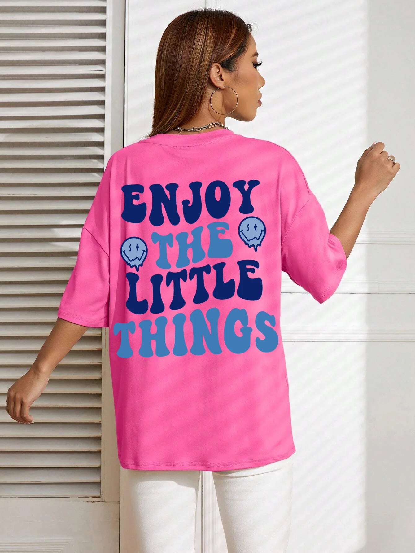 Person wearing a pink t-shirt with 'Enjoy the Little Things' text on the back.