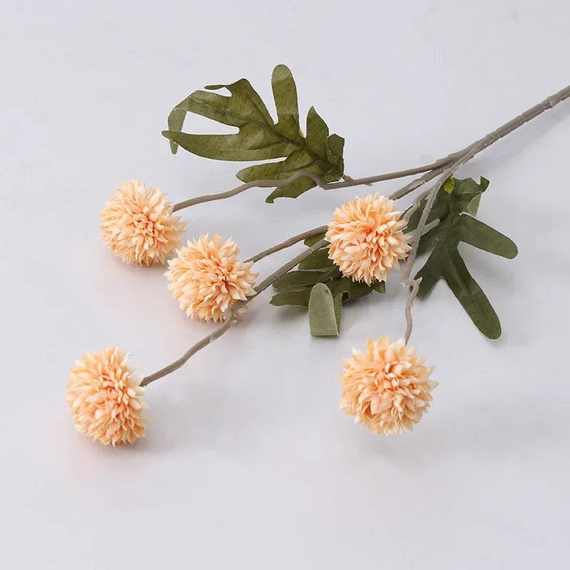 Branch with peach-colored flowers and green leaves on a light gray background