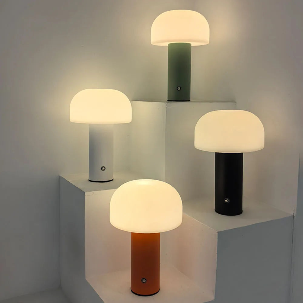 Set of four modern mushroom table lamps with different colored bases on a neutral background