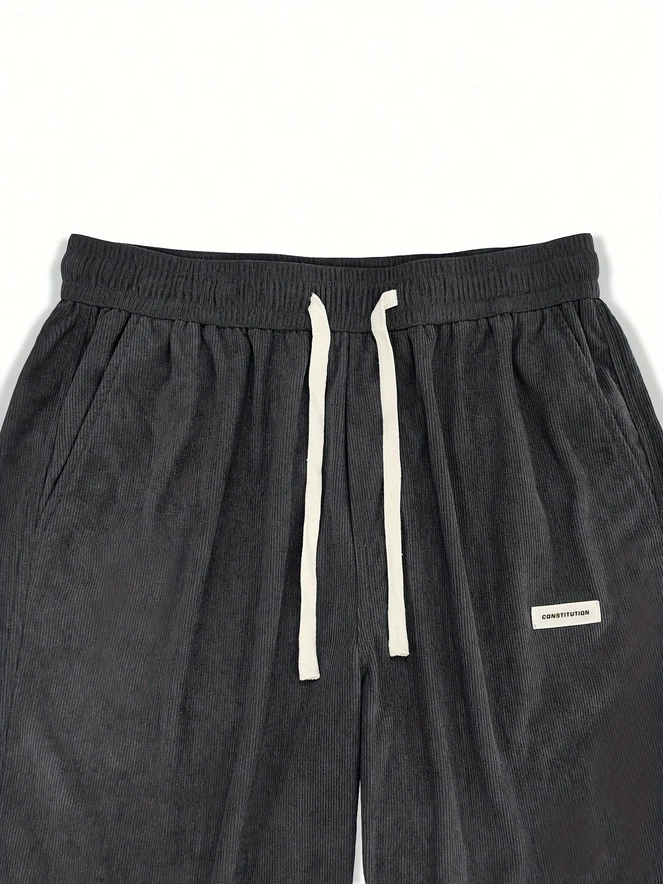 Dark gray sweatpants with a white drawstring and a small white label on a white background