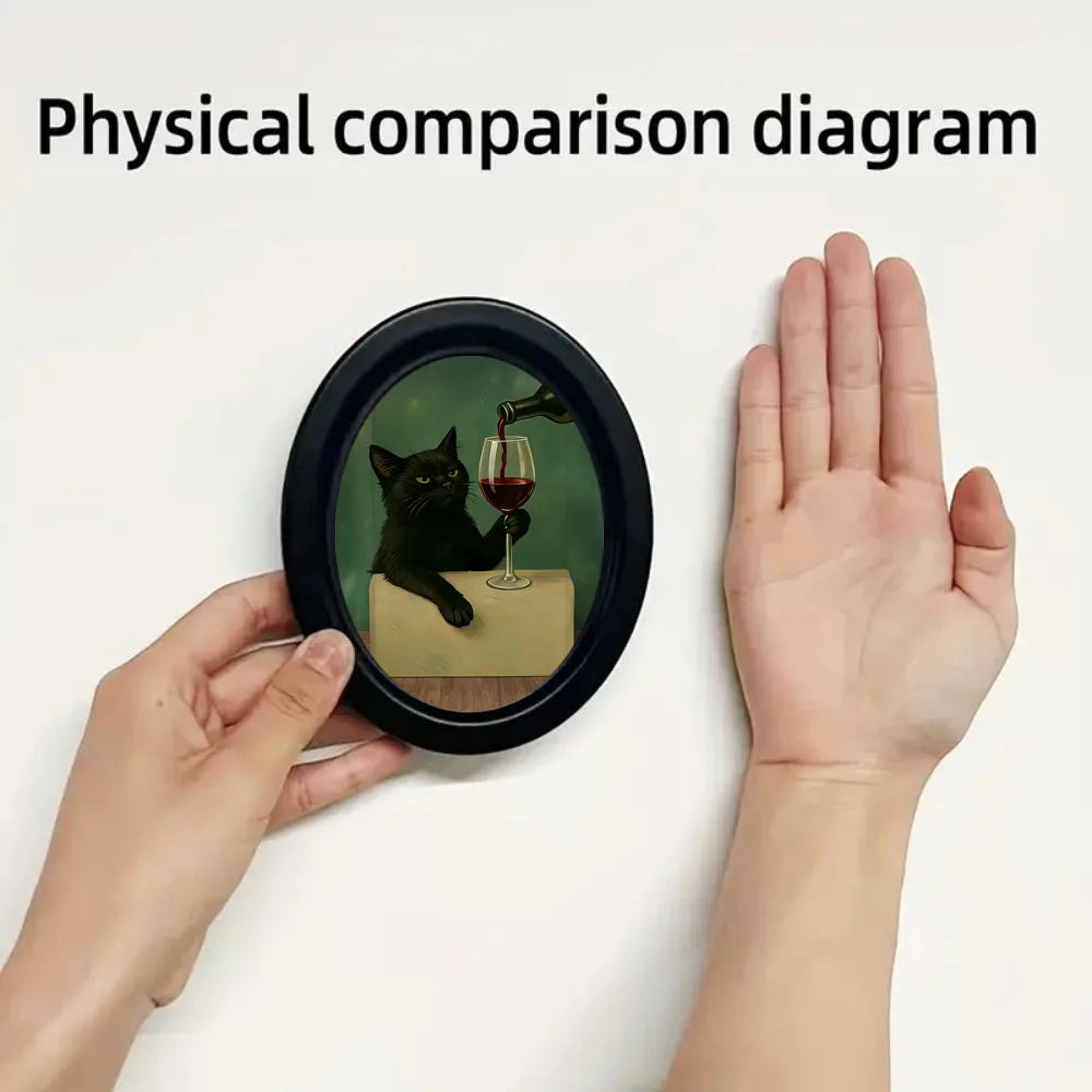 Small circular Framed poster with a black cat and wine glass design held between two hands against a white background.