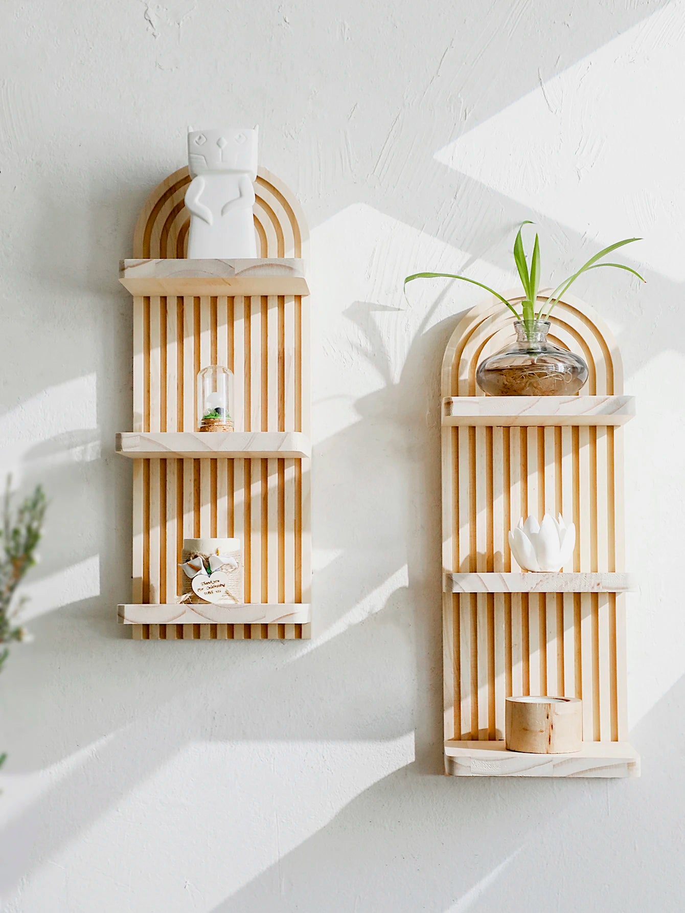 Two wooden wall shelves with decorative items against a white wall.