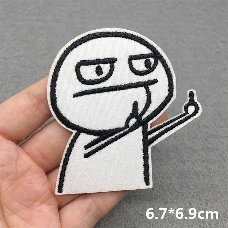 Hand holding a cartoon character patch with a gray background
