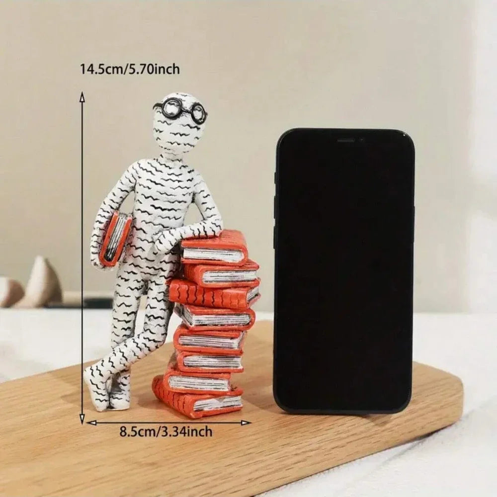 Small figurine with books and a smartphone for scale on a wooden surface