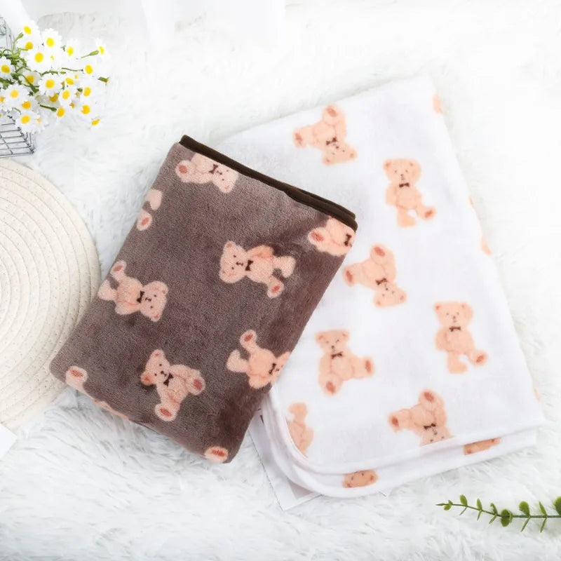 Two plush pet blankets with teddy bear patterns on a light surface.