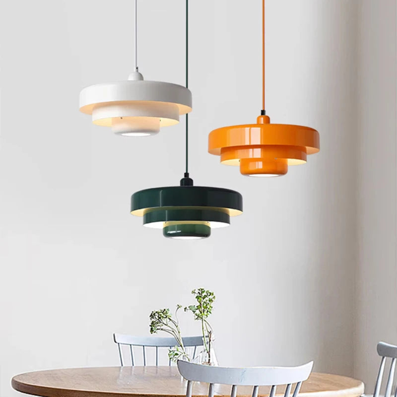 Three colorful pendant lights hanging above a dining table with chairs.