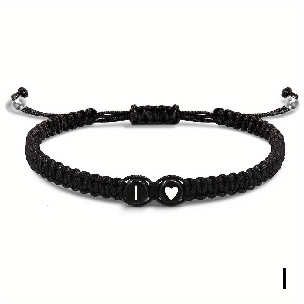Black braided bracelet with heart and round charm on a white background
