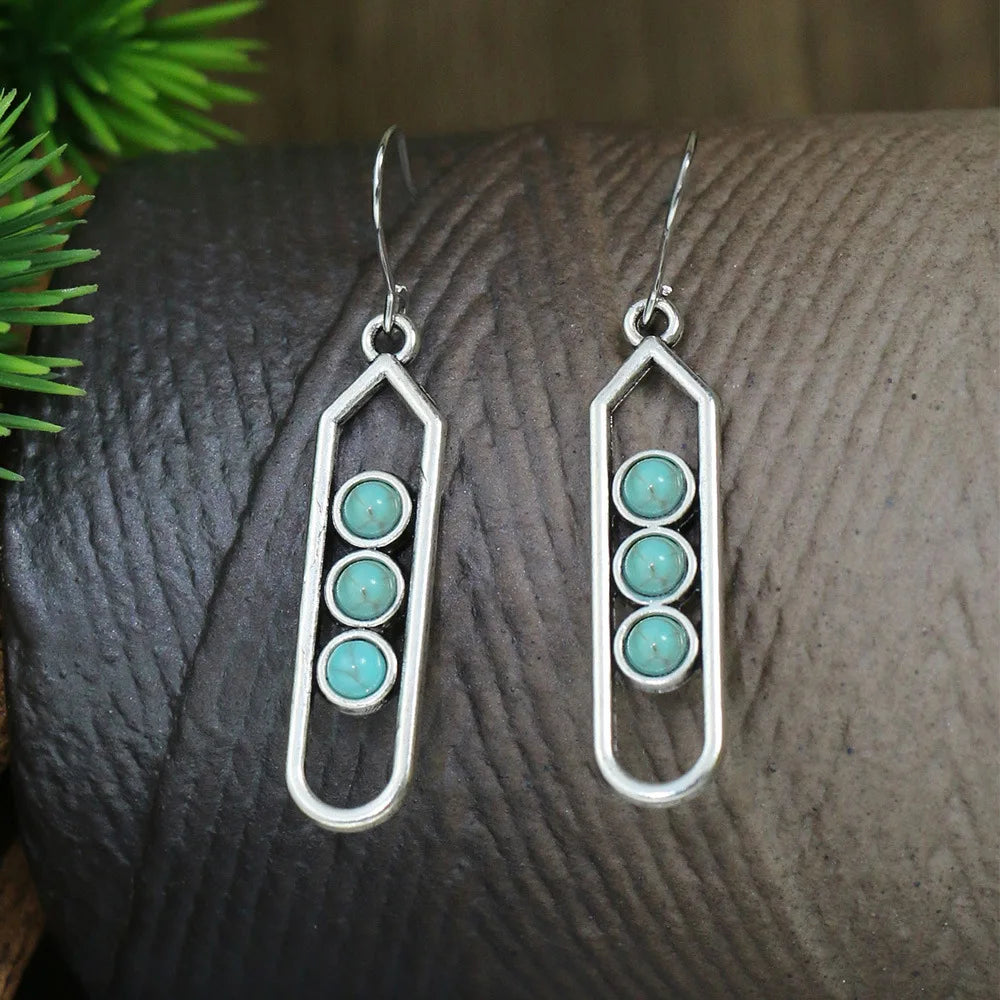 Silver earrings with turquoise stones on a textured surface