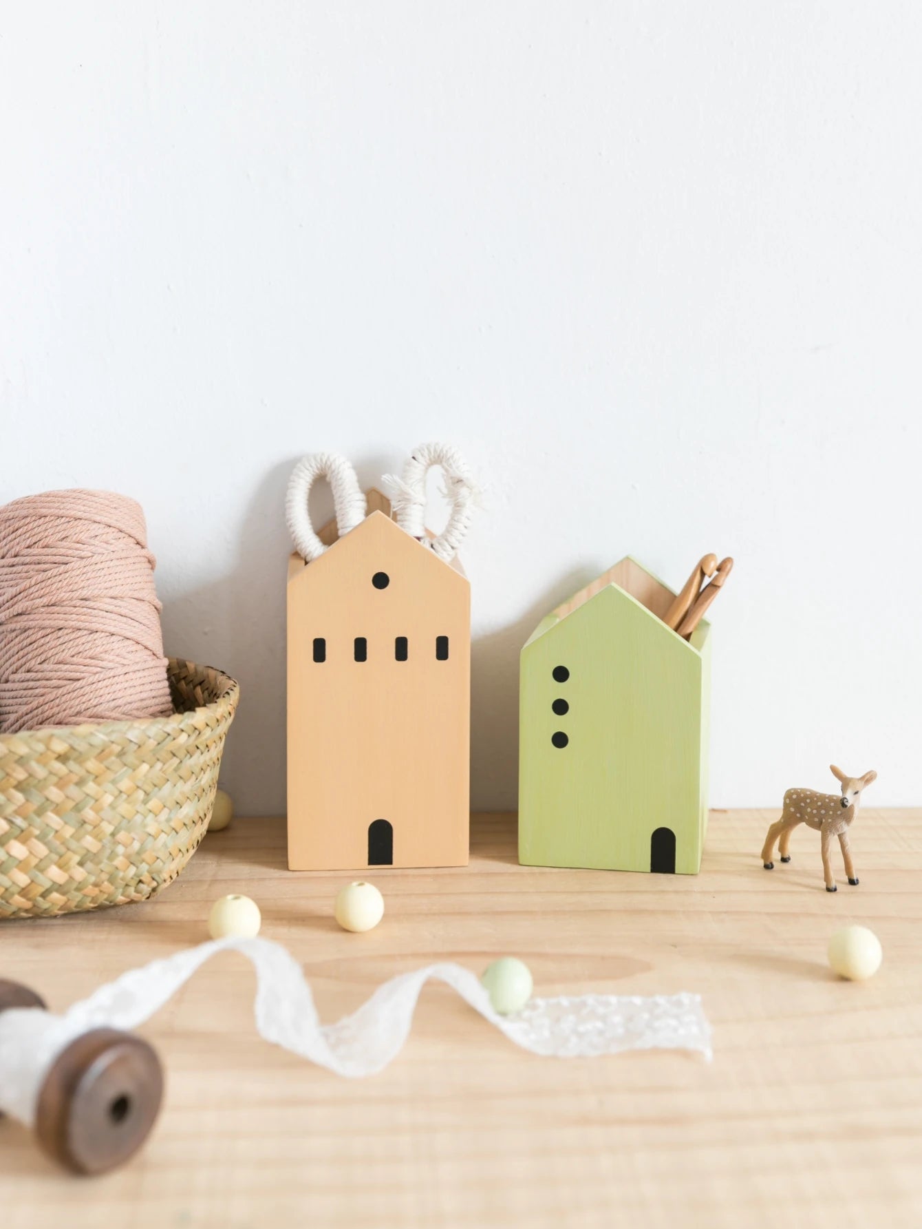Wooden house-shaped planters on a wooden surface with decorative items.