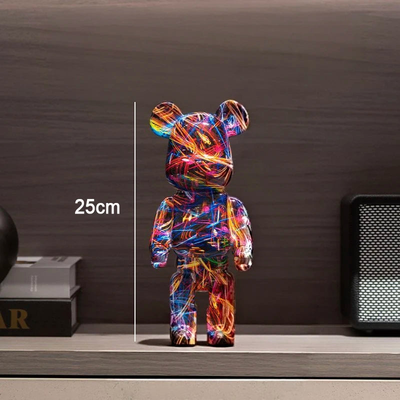 A colorful bear-shaped figurine standing on a shelf, covered in multicolored abstract line art. White text reads '25cm' with a vertical measurement line beside it.