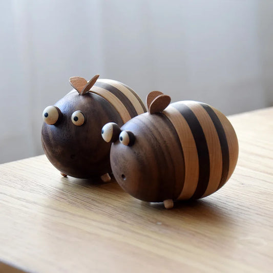 Two handcrafted wooden bee toothpick holders with striped natural wood finish displayed on a wooden tabletop as decorative kitchen accessories.