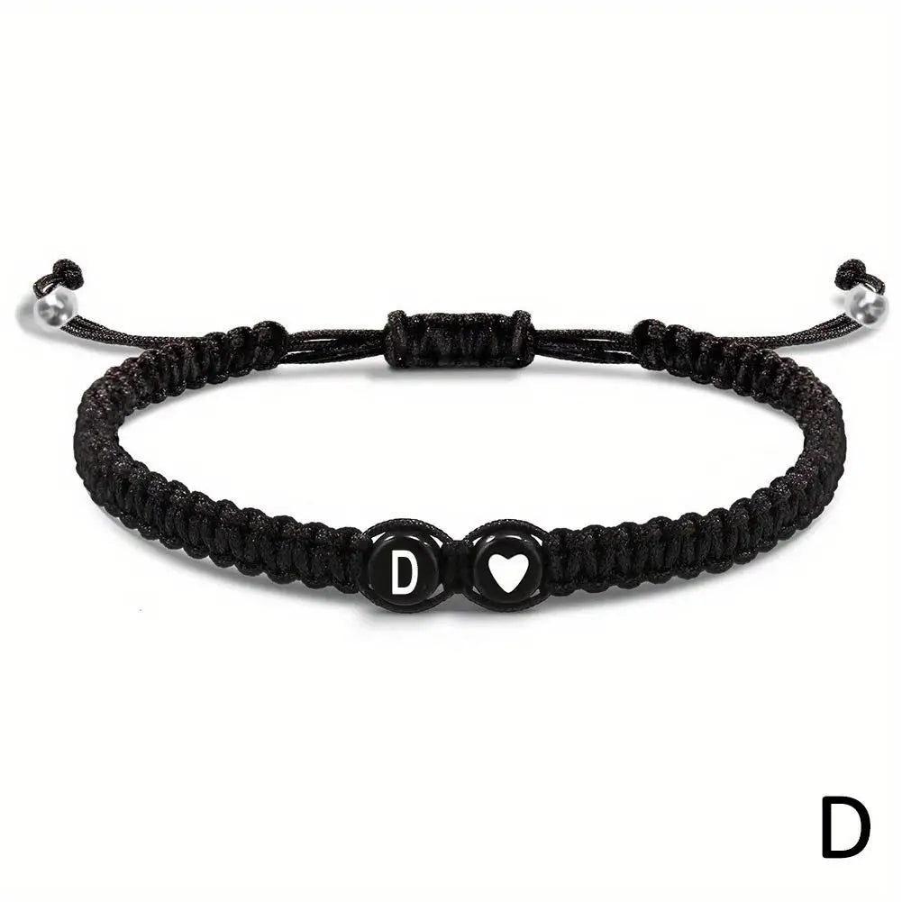 Black braided bracelet with letter 'D' and heart charm on a white background