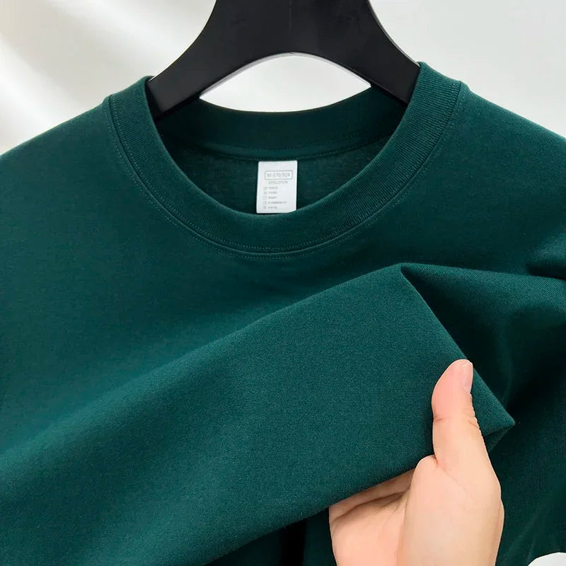 Green sweatshirt on a hanger with a hand holding it, against a white background