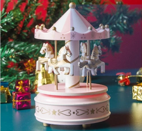 Pink carousel toy with horses on a blue surface with Christmas decorations in the background