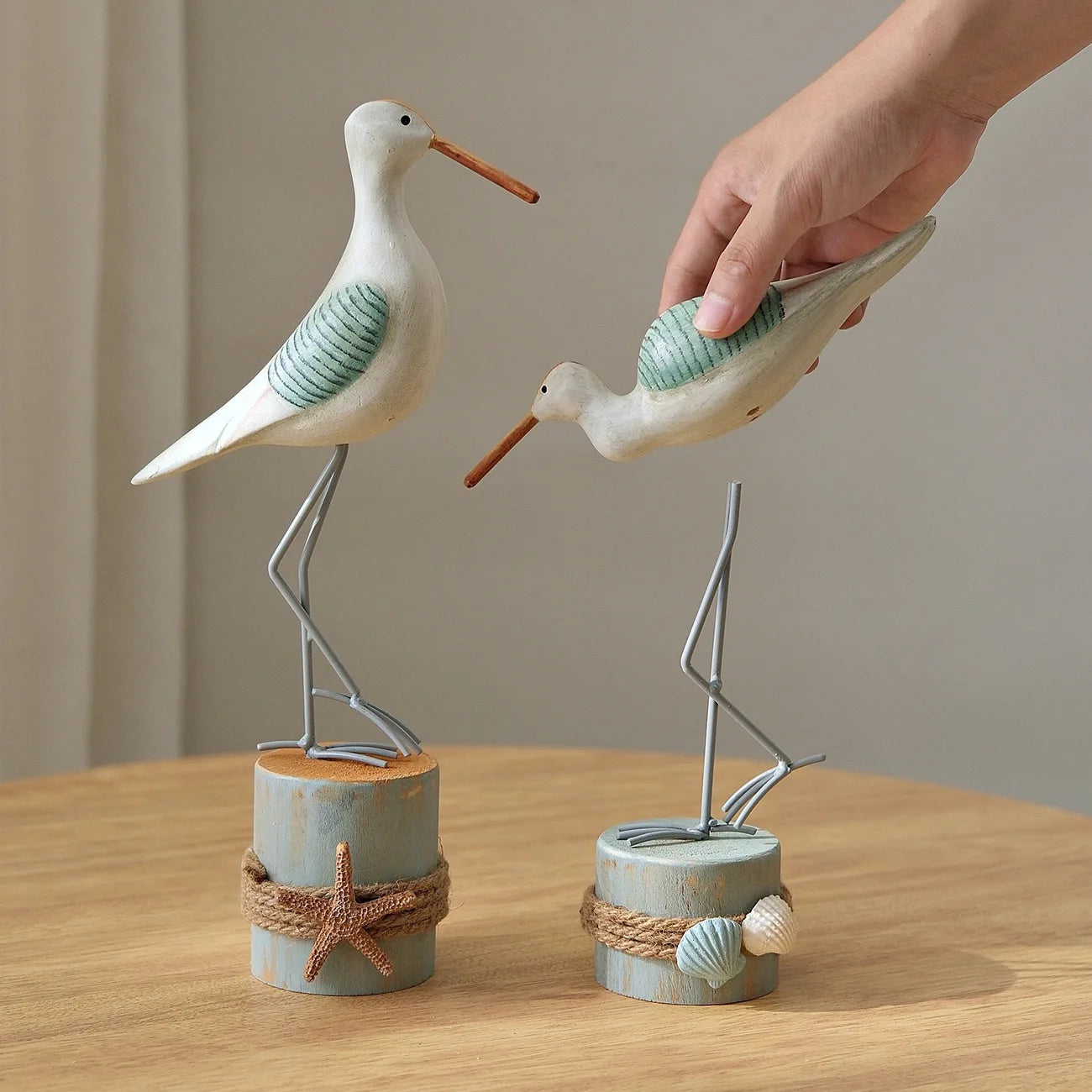 Decorative stilt birds on wooden stands with a hand interacting with one of them.