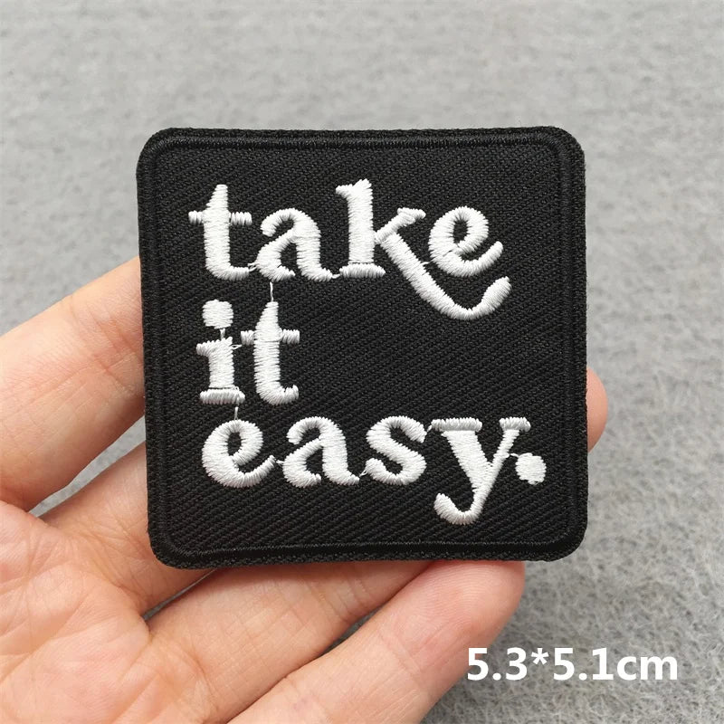 Black patch with 'take it easy' text held in a hand against a gray background