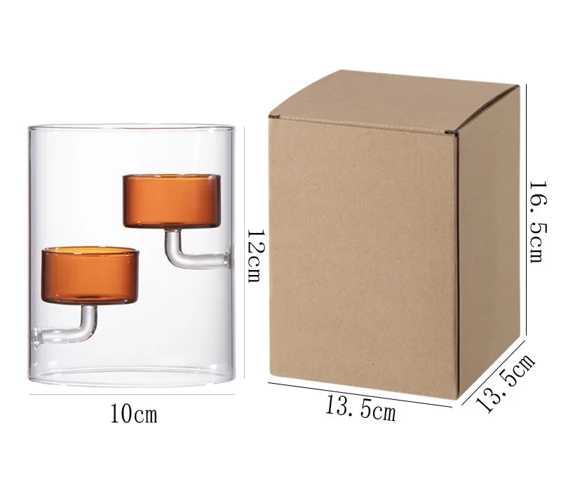 Glass candle holder with orange candle and cardboard box with dimensions on a white background