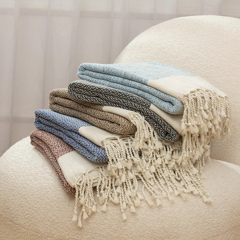 Stack of folded blankets with tassels on a beige chair