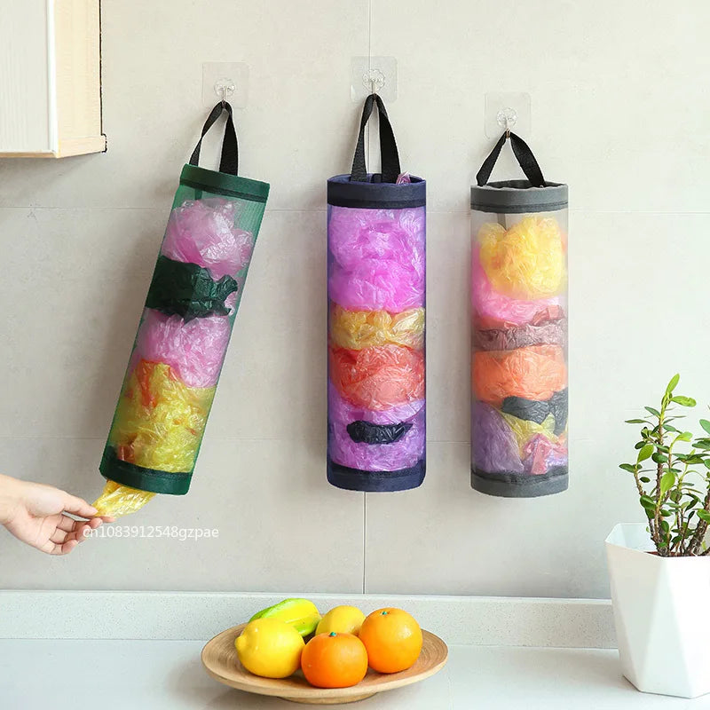 Three colorful cylindrical storage bags hanging on a wall above a kitchen counter with fruits.