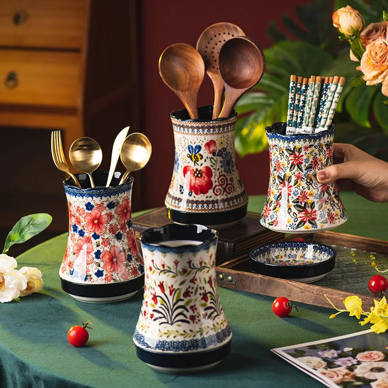 Decorative kitchen utensil holders with floral patterns on a table.