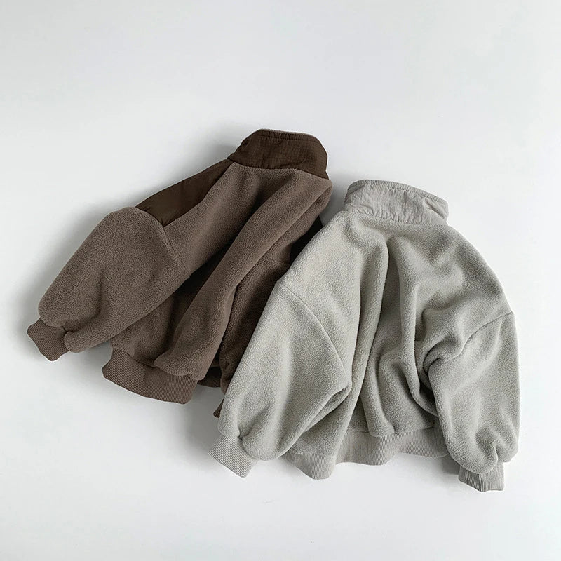Two fleece jackets, one brown and one gray, on a white background