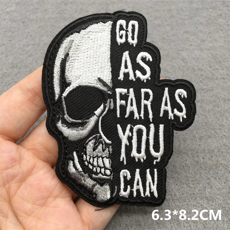 Skull patch with 'Go as far as you can' text held in a hand on a gray background