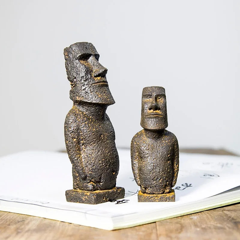 Moai-inspired resin ornaments with a distressed stone-effect finish displayed on a wooden surface.