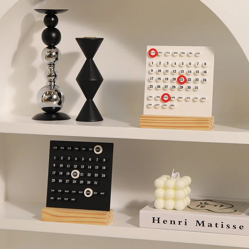 Two desk calendars on a shelf with decorative items