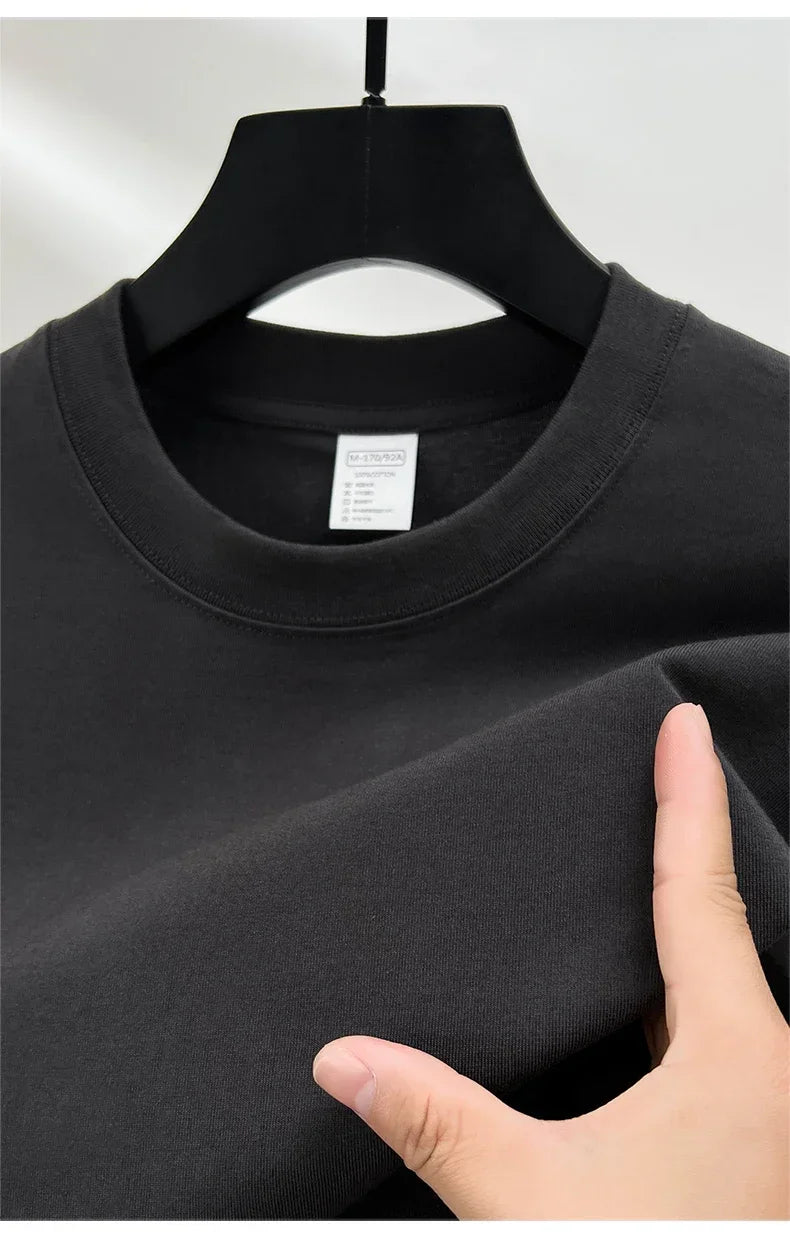 Black t-shirt on a hanger with a hand touching the fabric