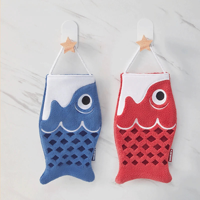 Two fish-shaped bath towels, one blue and one red, hanging on a white background.