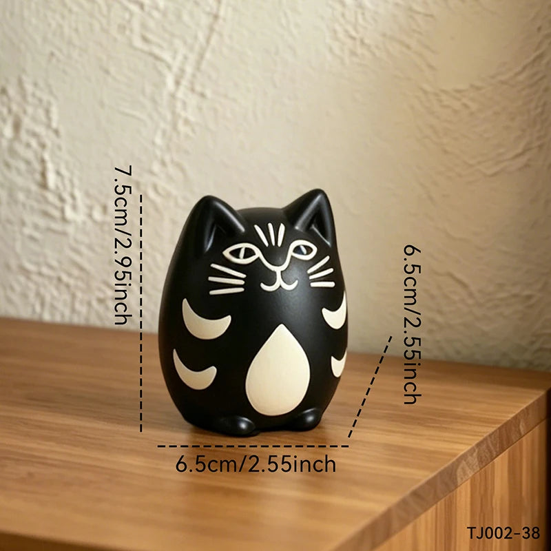 A black cat-shaped decorative object with cream-colored facial and body patterns, shown on a wooden surface against a textured beige wall. Measurement lines and text indicate dimensions of 7.