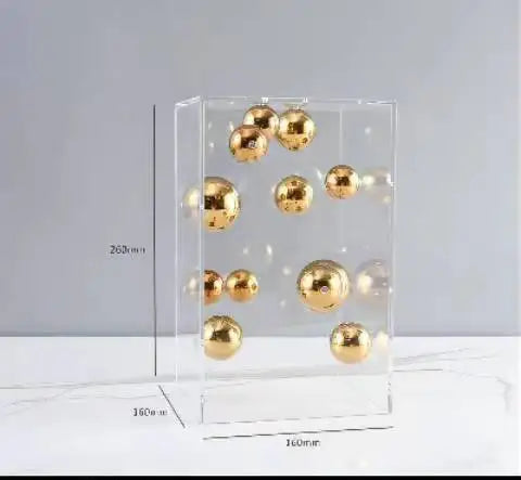 Clear display case with gold spherical objects on a gray background