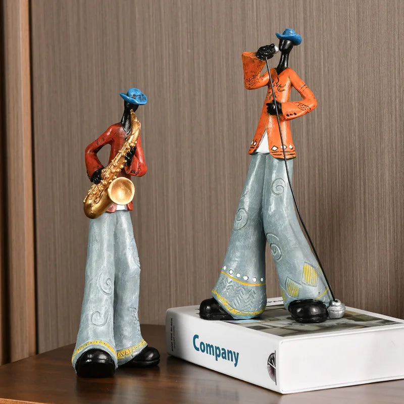 Two decorative figurines of musicians on a wooden surface with a brown background