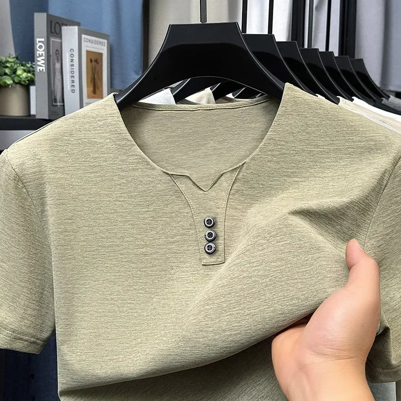 Green henley shirt on a hanger with a blurred indoor background
