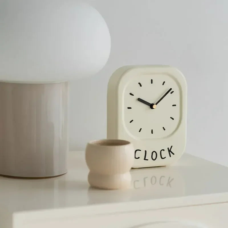 Small white clock with 'CLOCK' text on a white surface