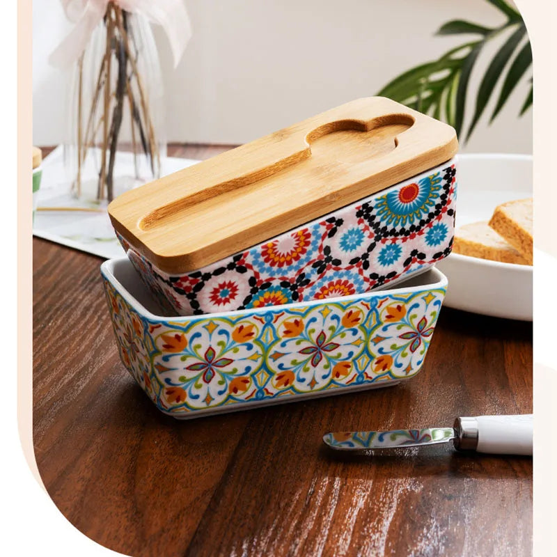 Country style ceramic butter dish with patterned design, wooden lid and butter knife on kitchen surface