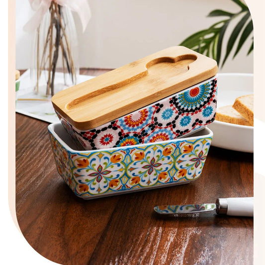 Country style ceramic butter dish with patterned design, wooden lid and butter knife on kitchen surface