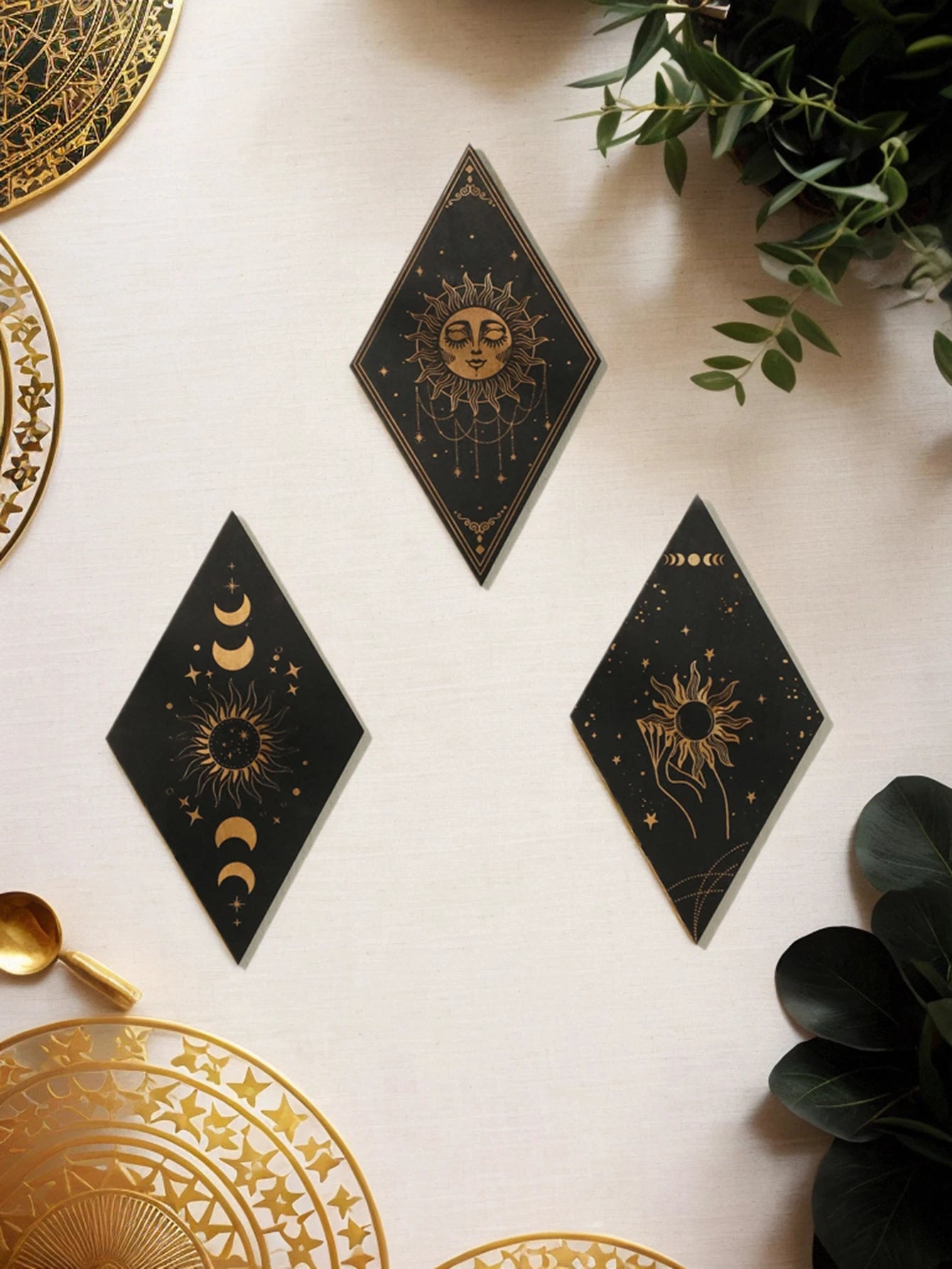 Decorative black and gold wall art pieces on a light surface with greenery.