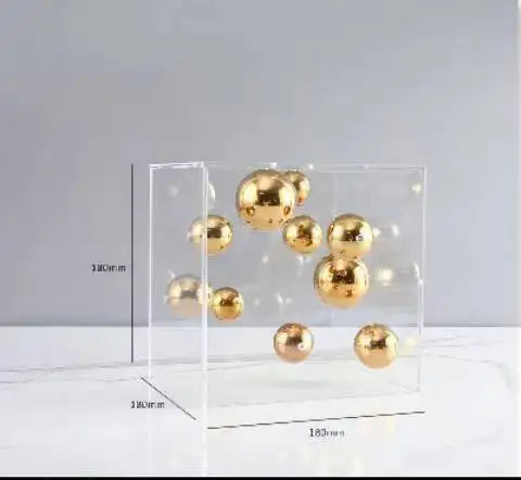 Clear acrylic block with gold spherical objects on a light gray background