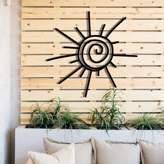 Decorative metal sun wall art on a wooden panel wall with plants and pillows below.