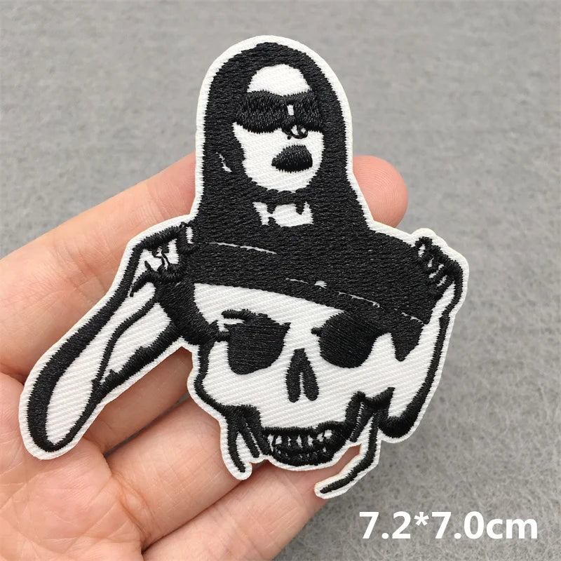 Embroidered patch with a skull design held by a hand on a gray background