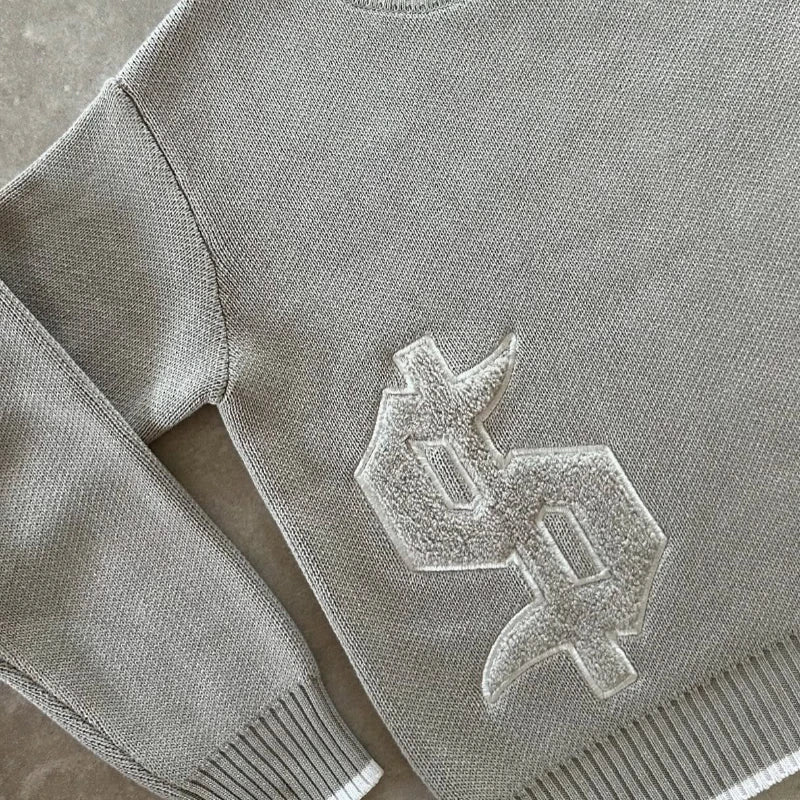Gray sweater with a logo on a concrete surface