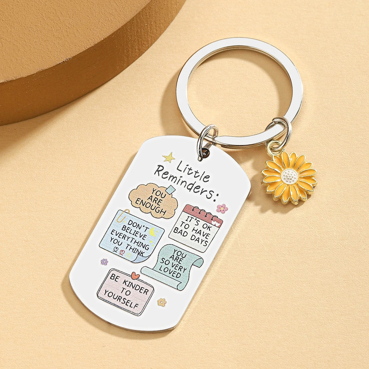Keychain with motivational quotes and a sunflower charm on a beige background
