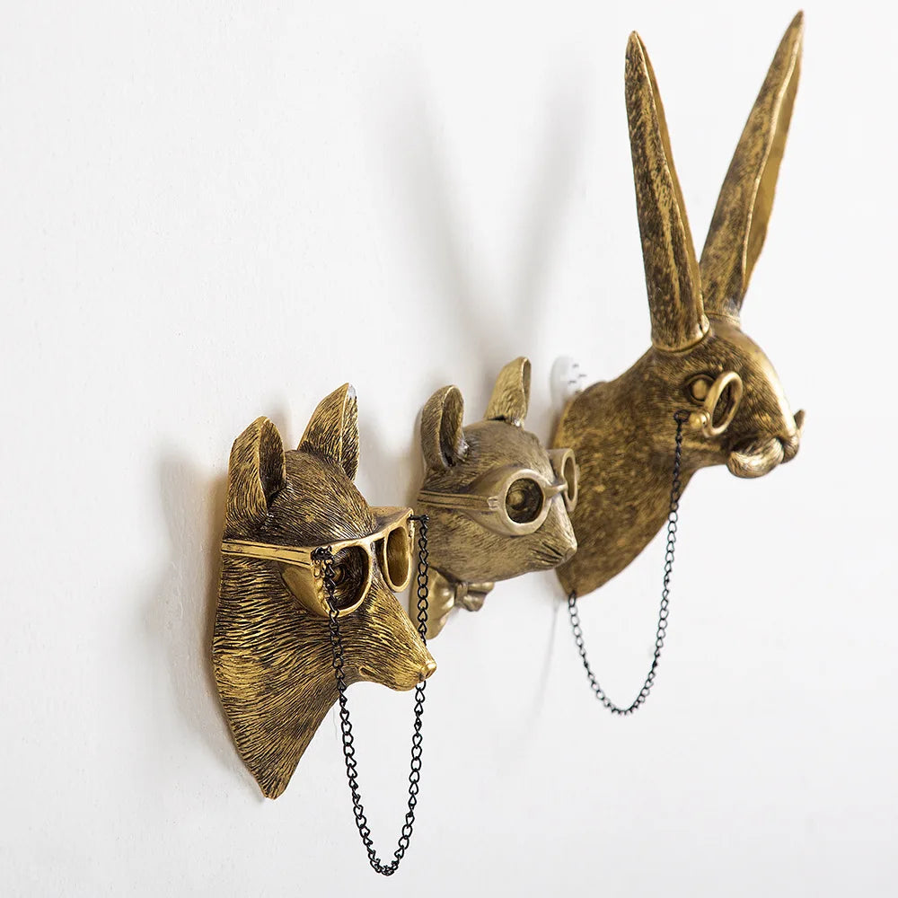 Three bronze animal head wall hooks with chains on a white background